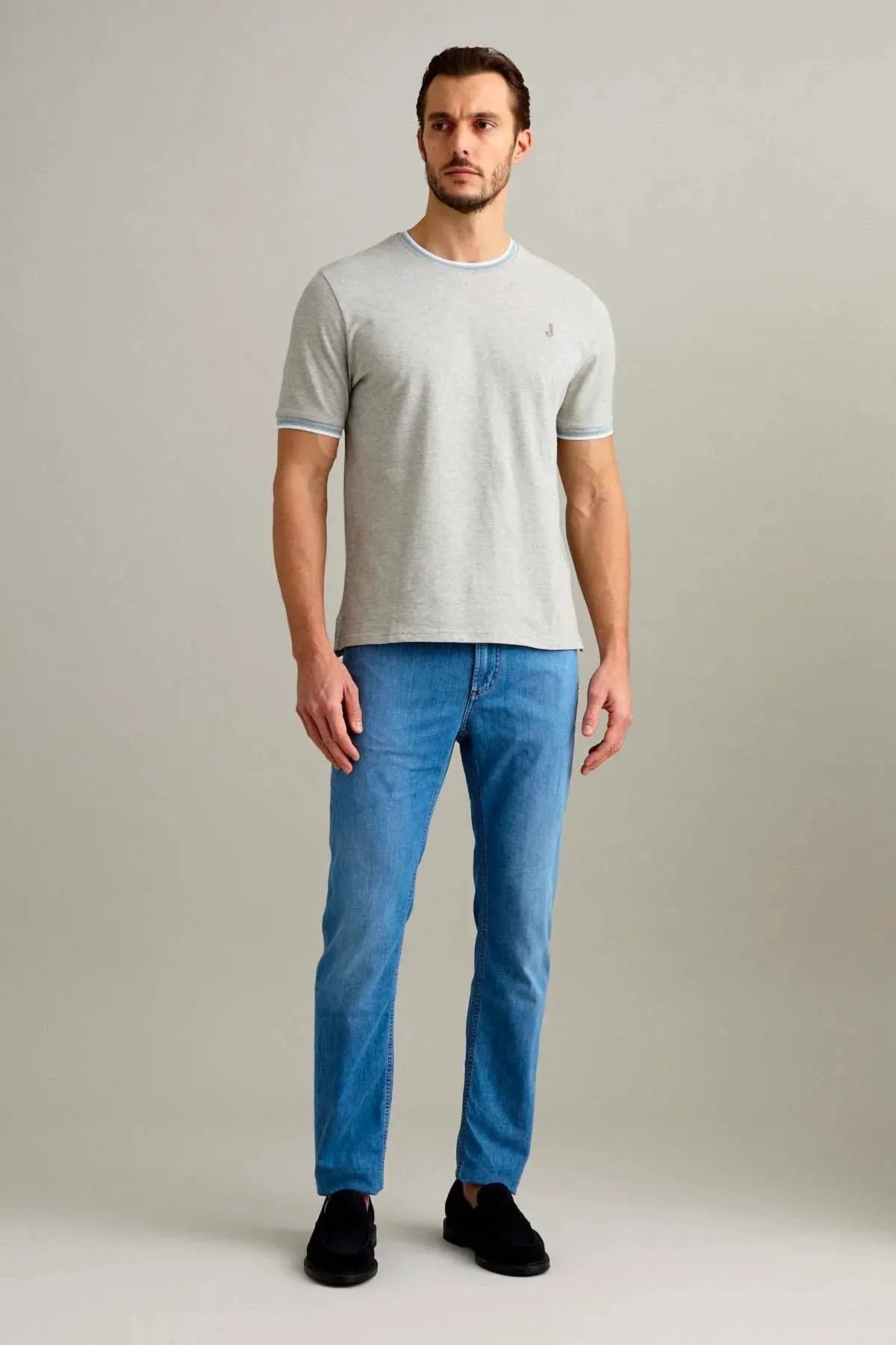 Uomo con t-shirt grigia e jeans denim dritti, stile casual elegante.