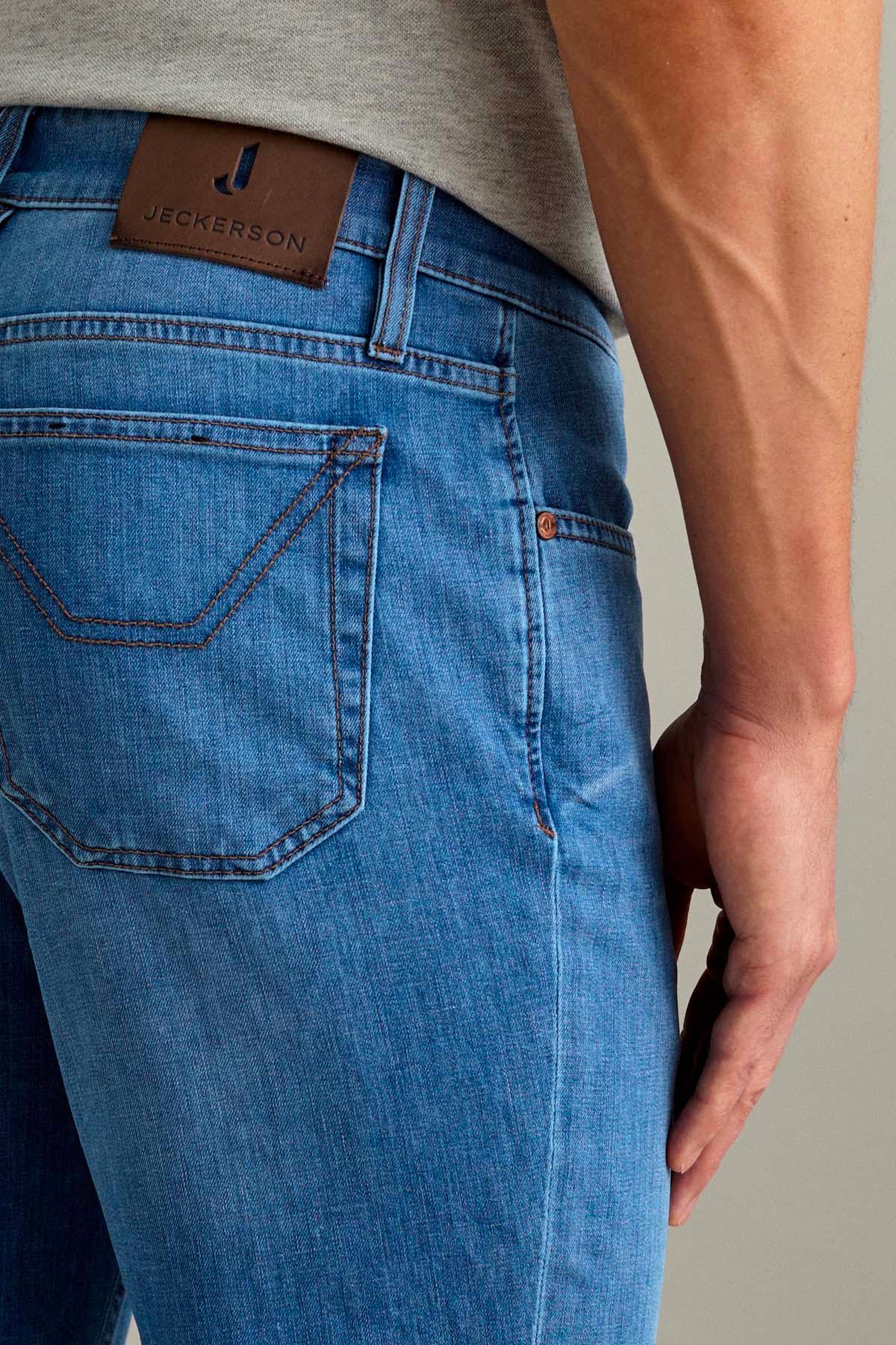Dettaglio posteriore jeans uomo denim chiaro con etichetta in pelle e tasche a vista.