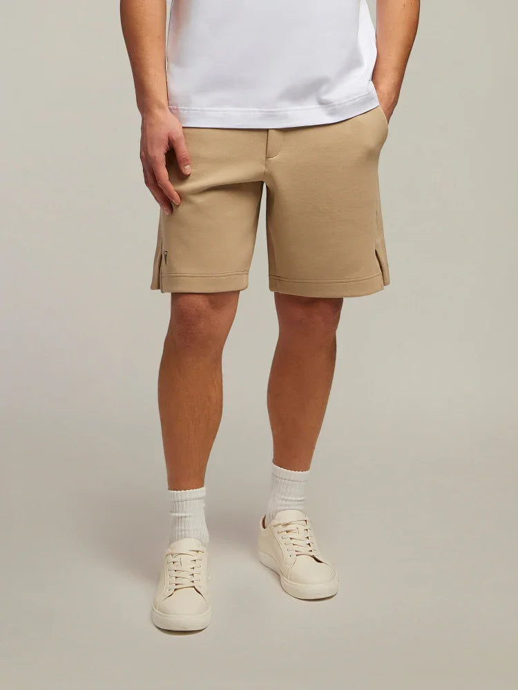 Shorts beige uomo in cotone con spacchi laterali, abbinati a sneakers bianche e calzini