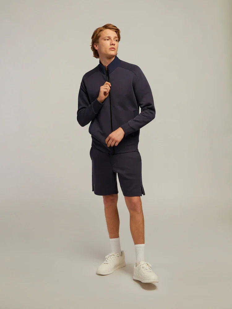 Modello uomo indossa completo felpa e bermuda blu navy sportivo con sneakers bianche