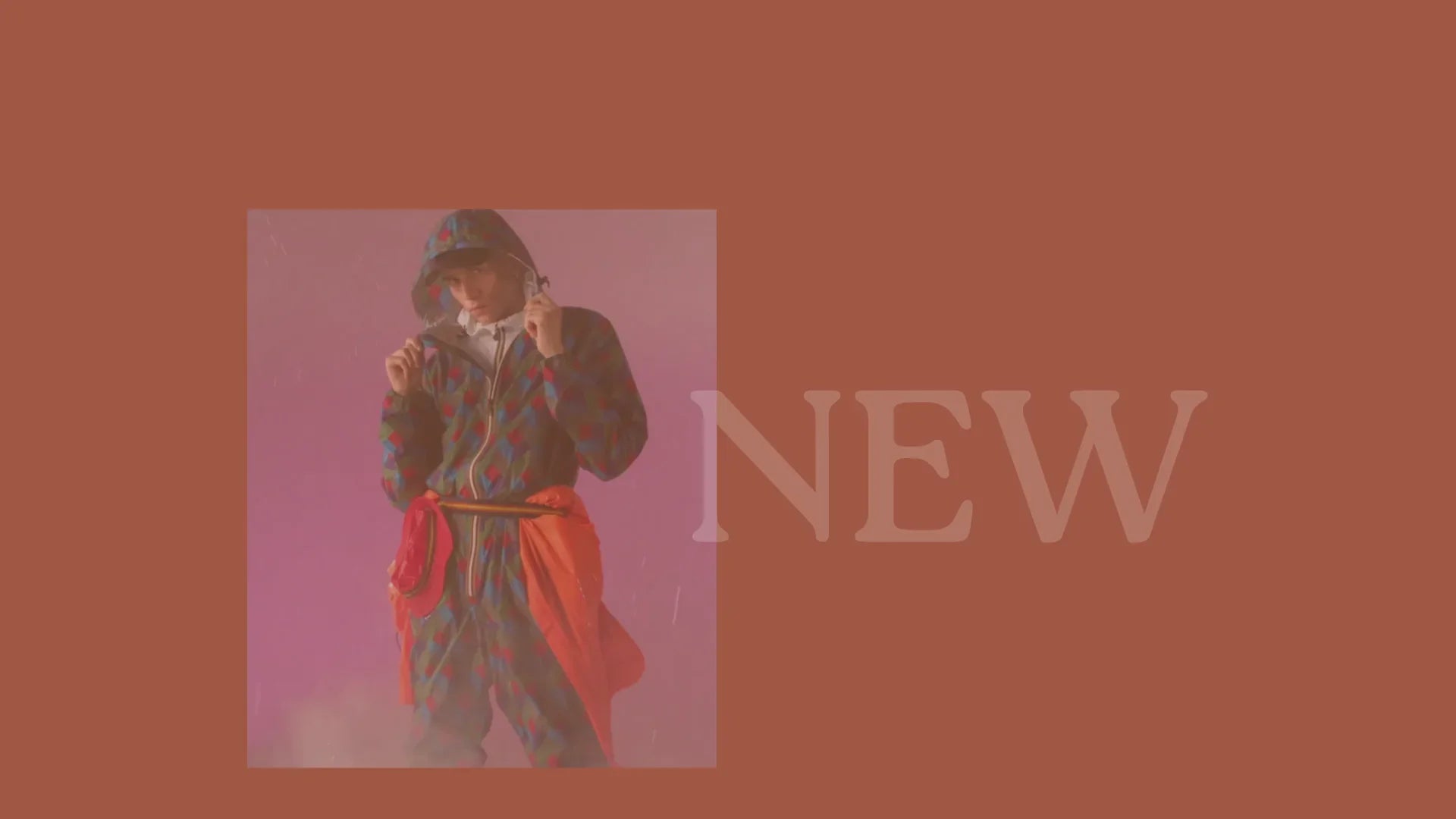 Modella con giacca a fantasia geometrica e cappuccio, pantaloni coordinati, fondo rosso, testo NEW.
