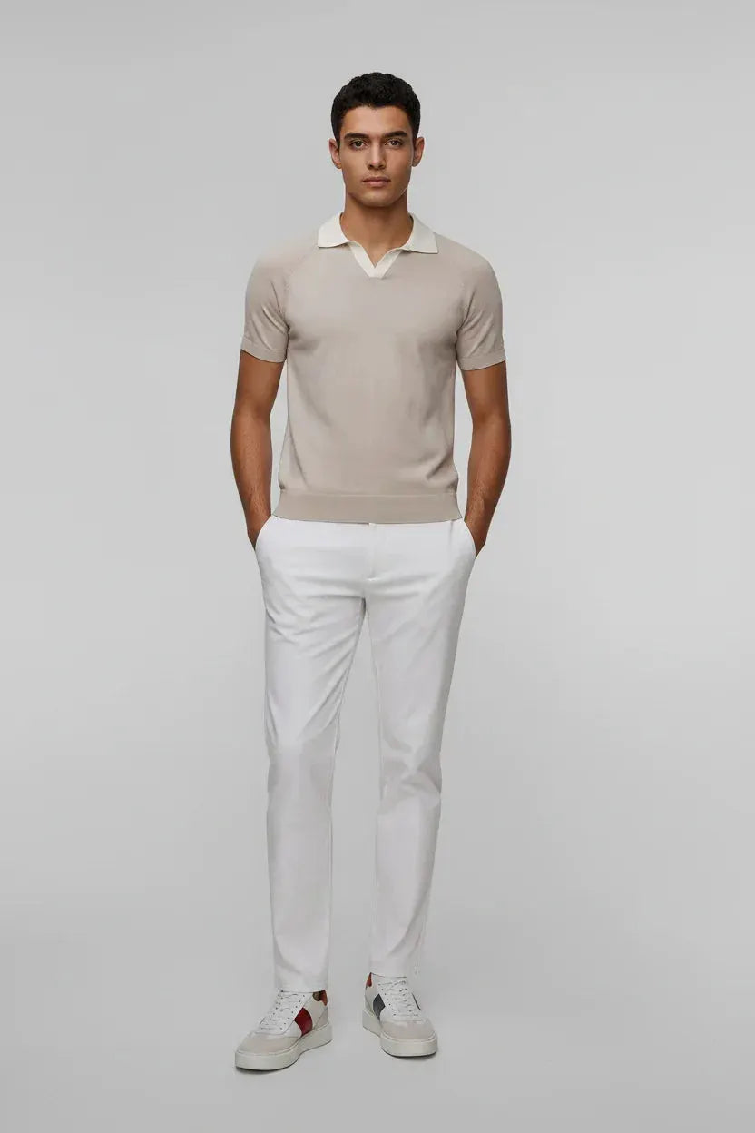 Uomo con polo beige a maniche corte, pantaloni bianchi e sneakers, moda uomo elegante.
