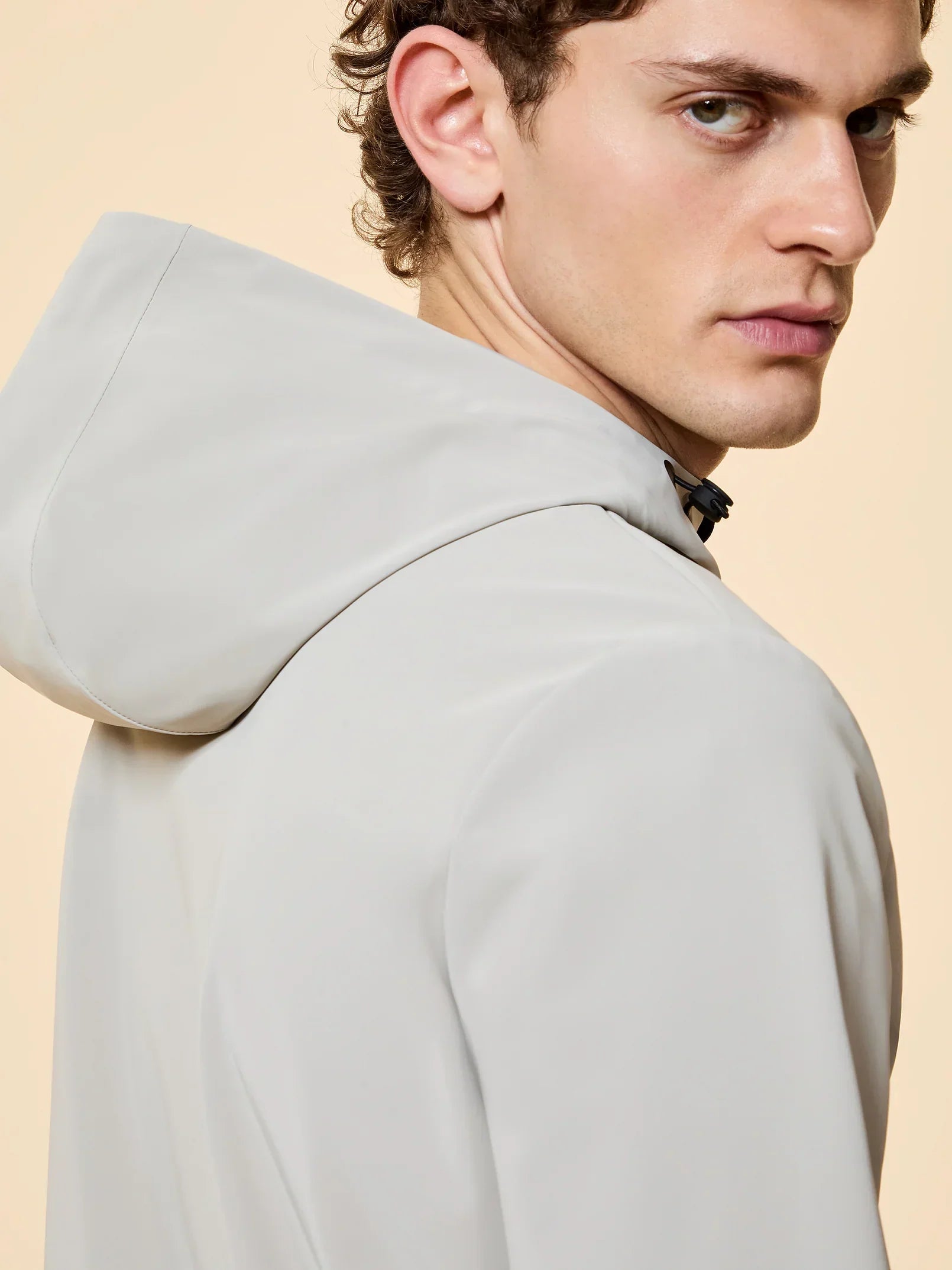 Uomo con giacca impermeabile beige chiaro con cappuccio, moda uomo elegante.