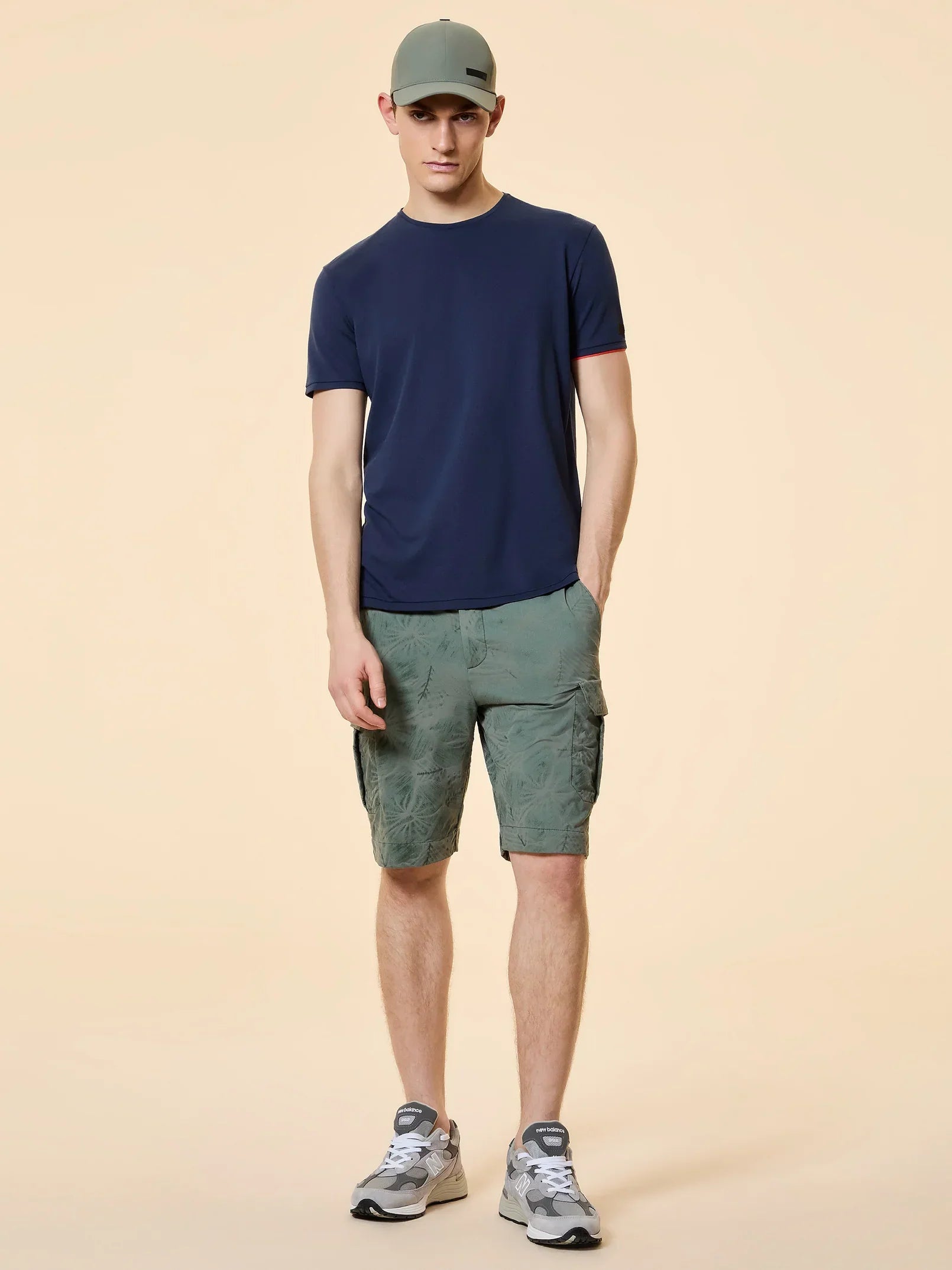 Uomo con t-shirt blu, bermuda cargo verdi, cappellino grigio e sneakers, moda casual uomo