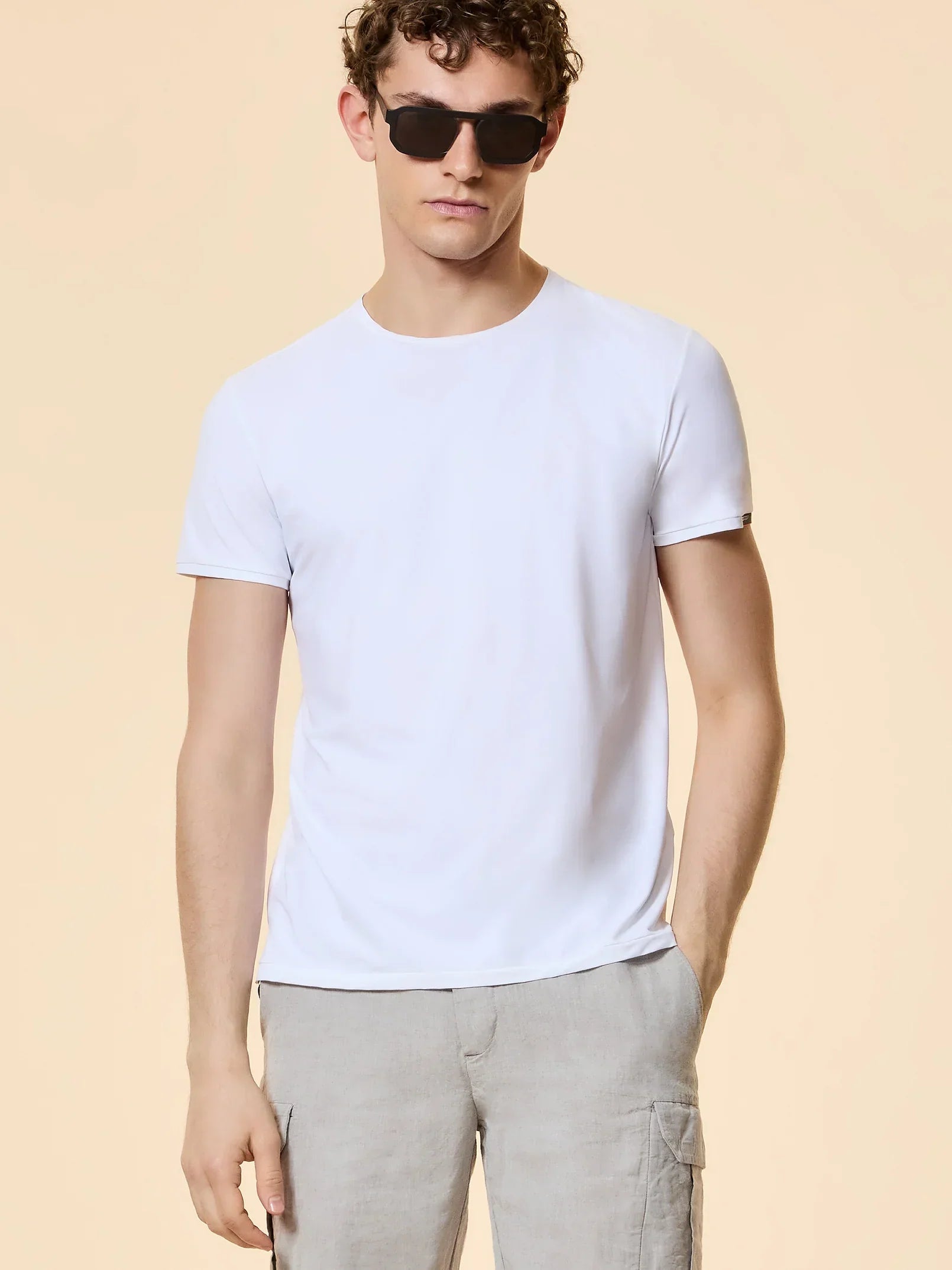 Modello indossa t-shirt bianca uomo, pantaloni lino beige, stile casual estivo