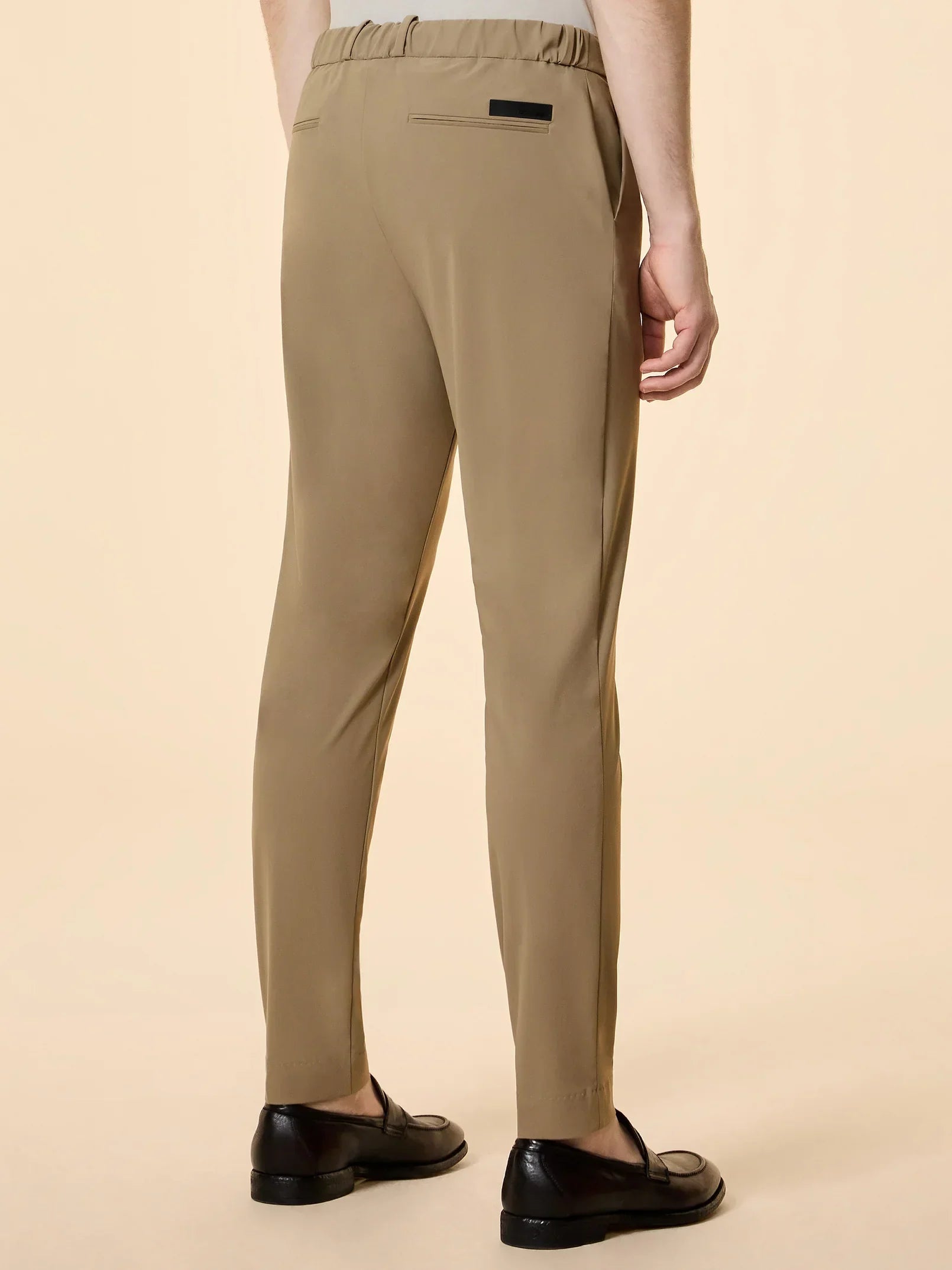 Pantaloni uomo beige eleganti con elastico in vita e scarpe nere, vista posteriore