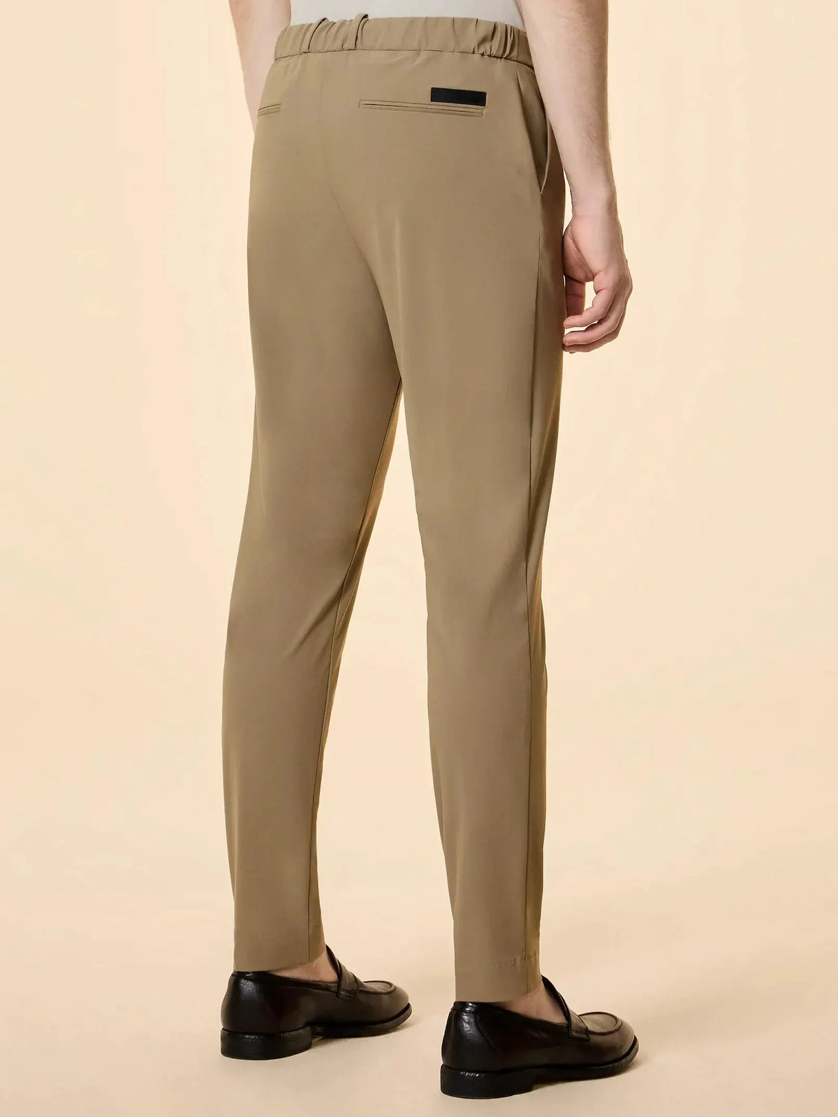 Pantaloni uomo beige eleganti con elastico in vita e scarpe nere, vista posteriore