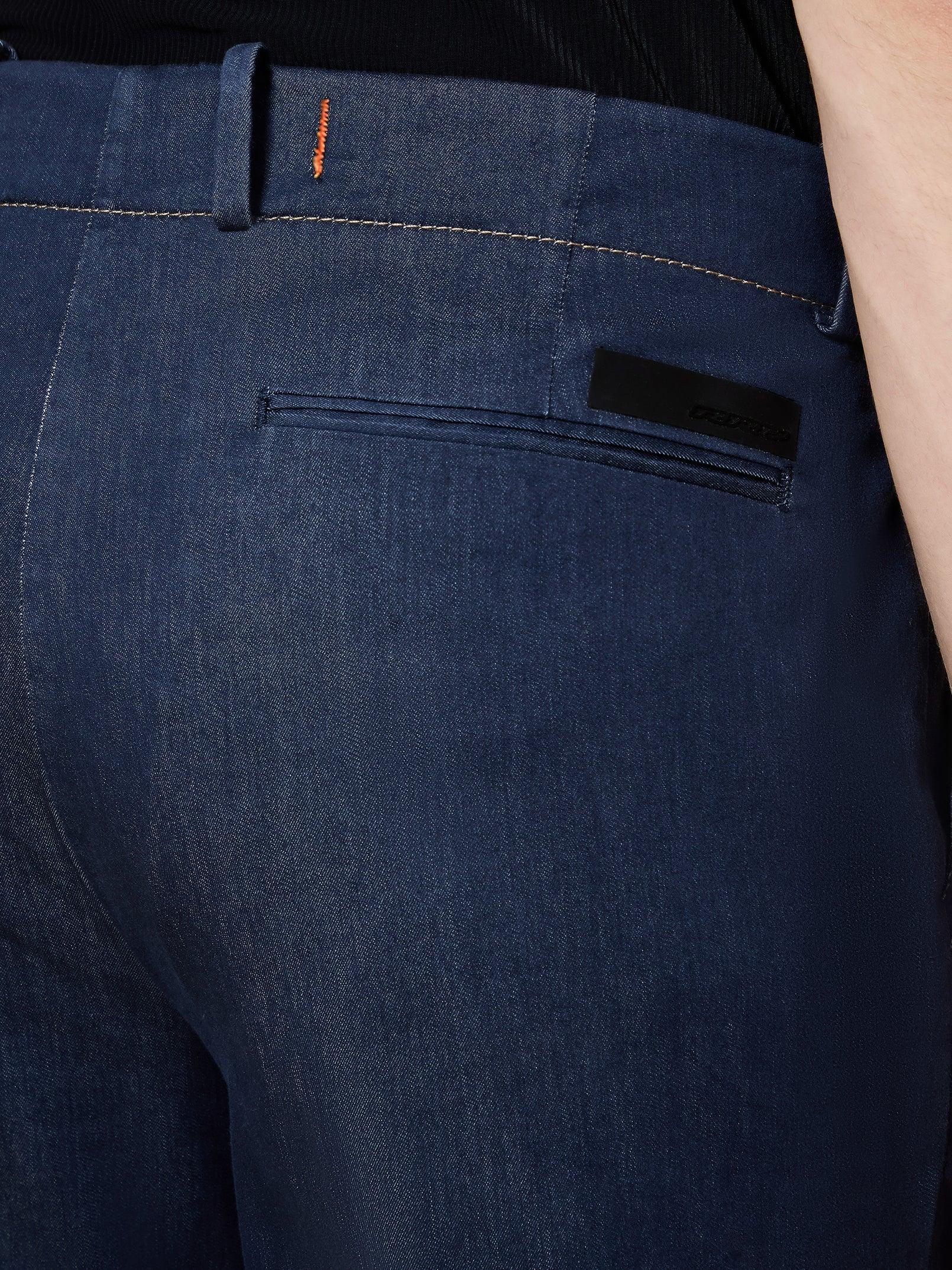 Dettaglio tasca posteriore pantaloni uomo in denim blu, cuciture a contrasto.
