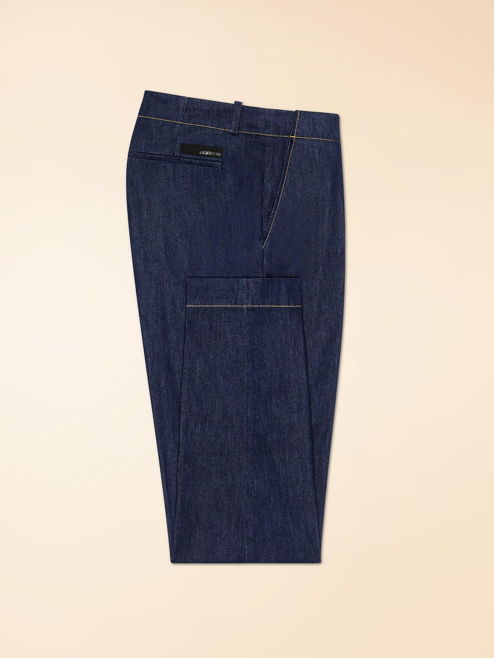 Pantalone uomo in denim blu con tasca posteriore e cuciture a contrasto su sfondo beige.