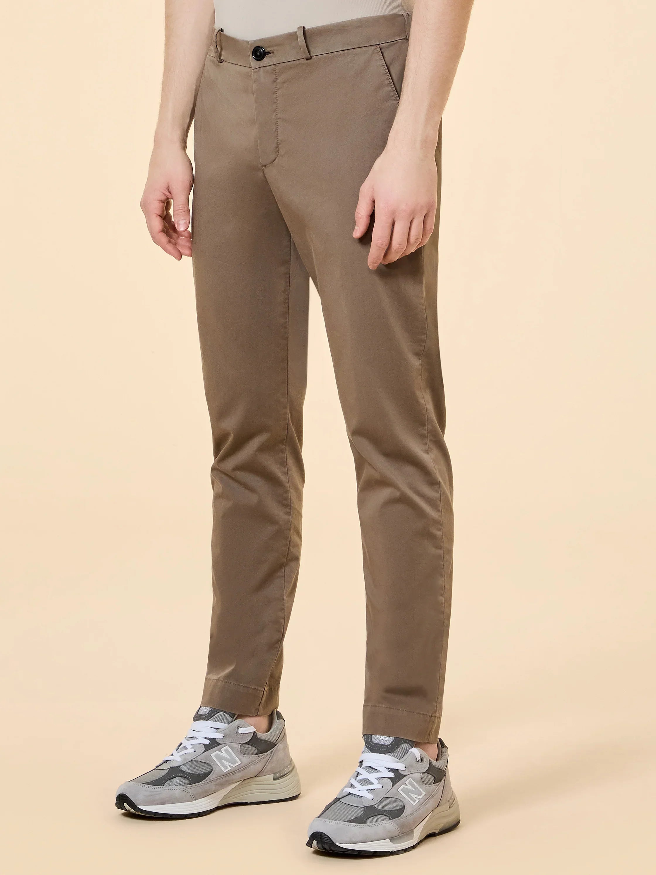 Pantaloni chino uomo beige abbinati a sneakers grigie, stile casual elegante
