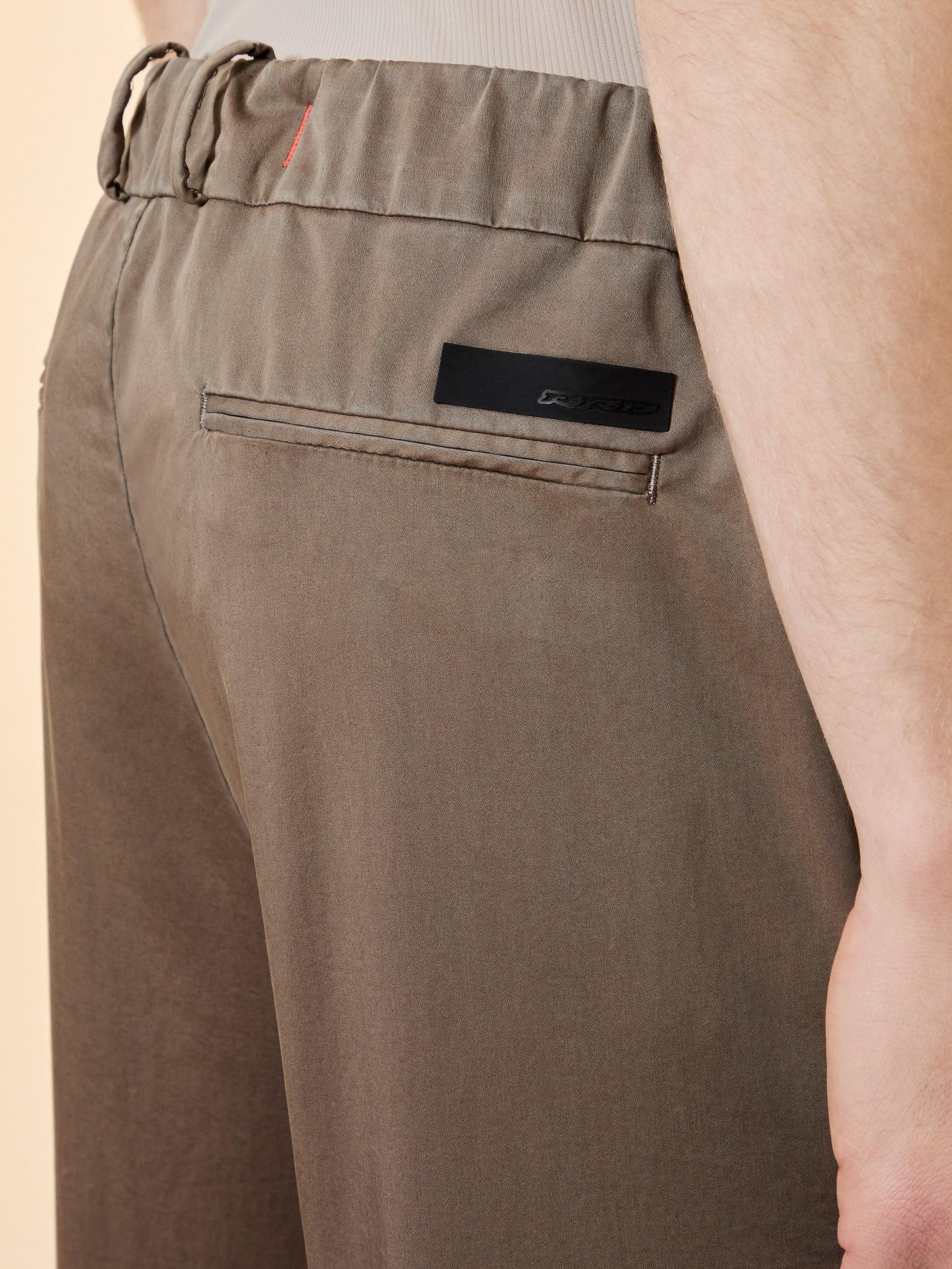 Dettaglio pantalone uomo beige con tasca posteriore e cintura elastica, abbigliamento casual