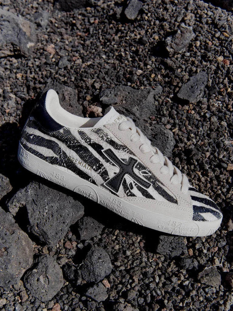 Sneaker uomo animalier bianca e nera su terreno vulcanico, dettaglio motivo zebrato