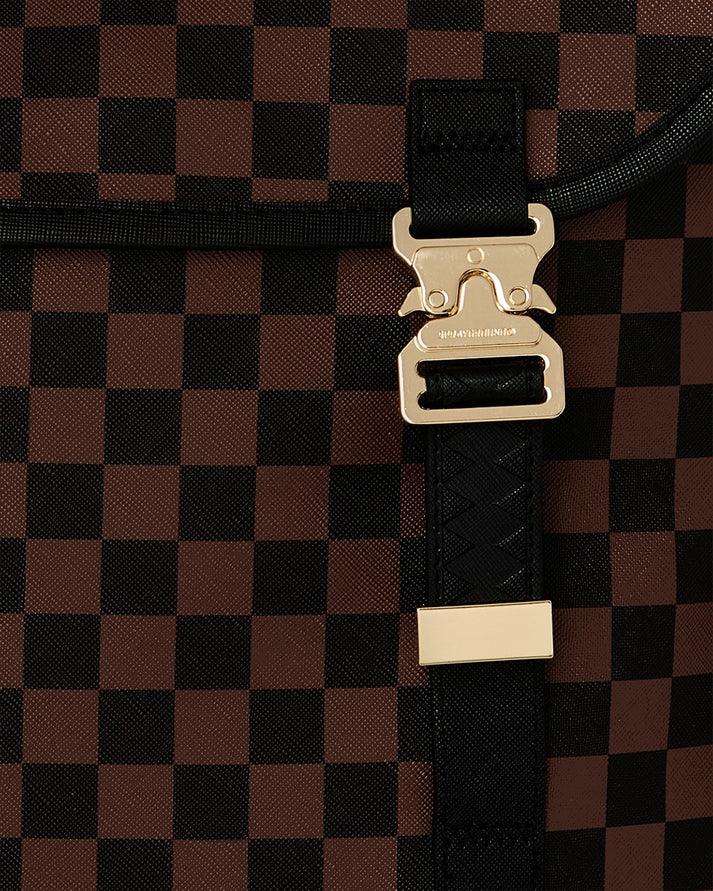 Dettaglio di una borsa con motivo a scacchi marrone e nero e fibbia dorata elegante.