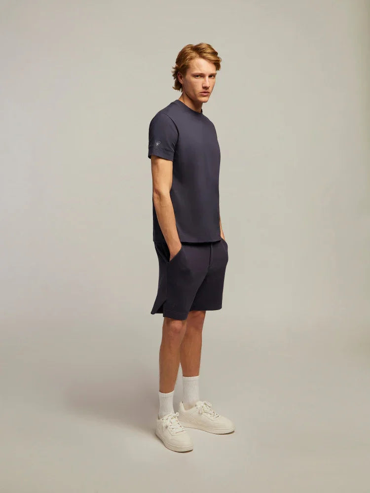 Modello uomo con t-shirt e shorts blu navy, calzini bianchi e sneakers, stile casual.