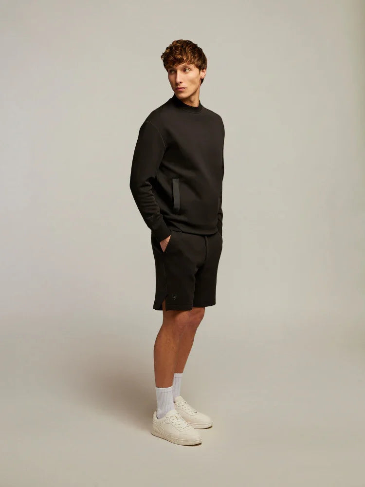 Modello uomo con felpa e bermuda neri, sneakers bianche, stile casual moda uomo