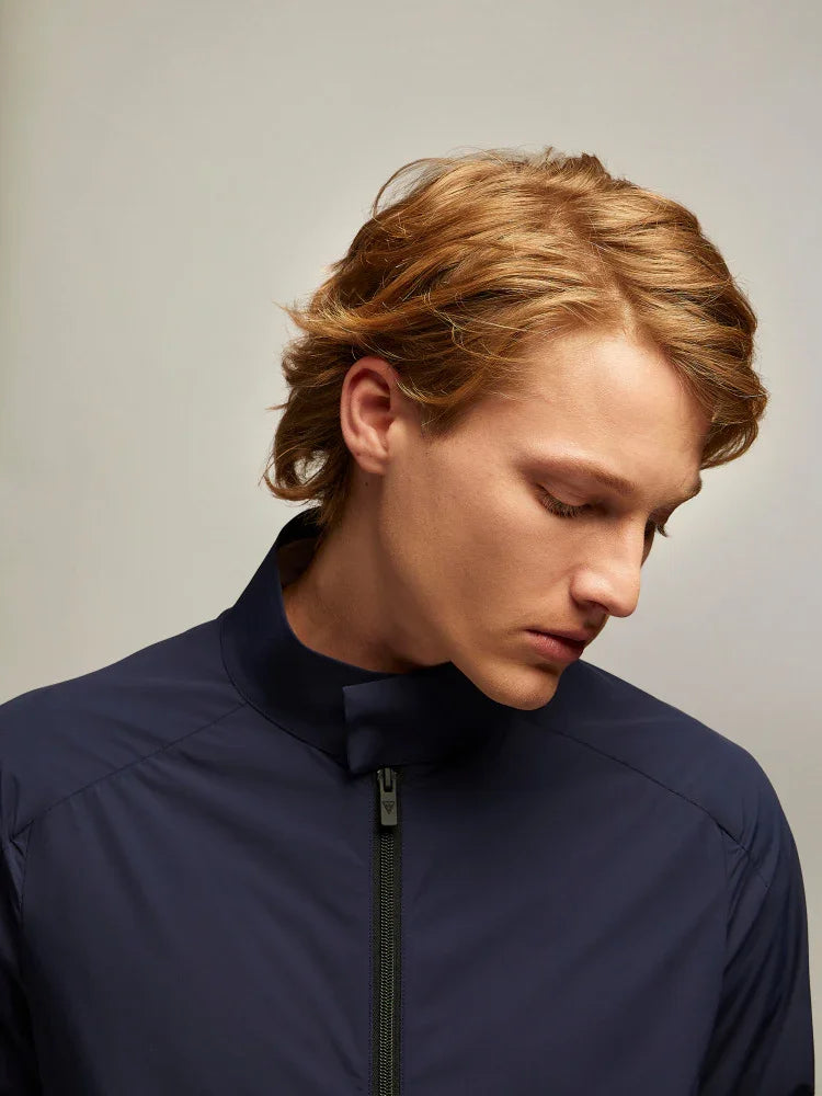 Giovane uomo con giacca tecnica blu navy, zip frontale, stile casual elegante