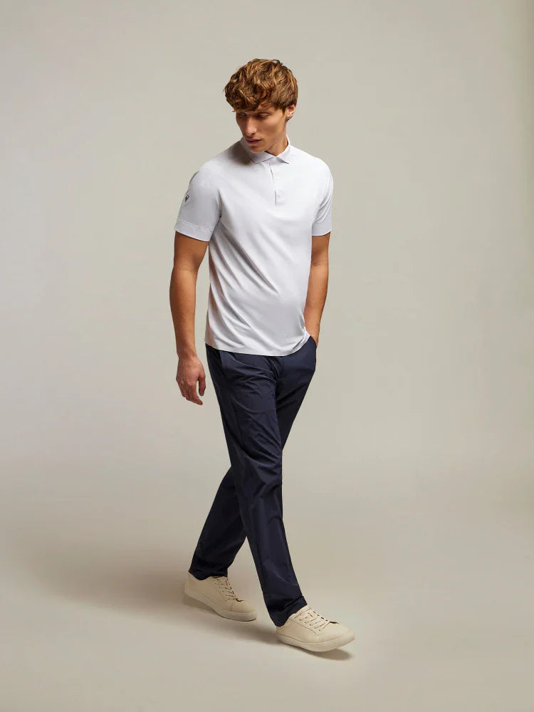 Uomo con polo bianca e pantaloni blu navy, sneakers beige, moda elegante casual