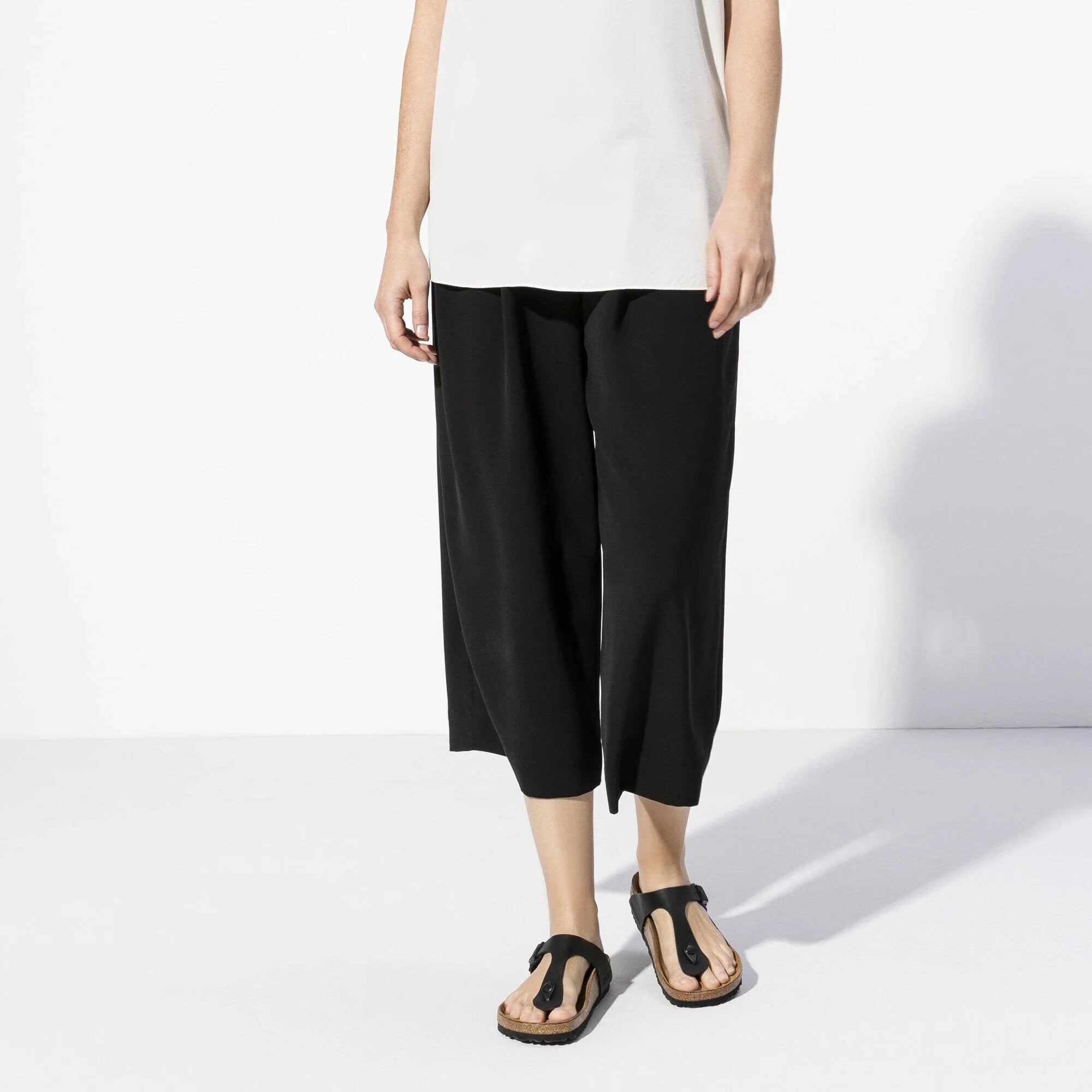 Pantaloni donna neri ampi alla caviglia con sandali bassi neri, stile minimal chic