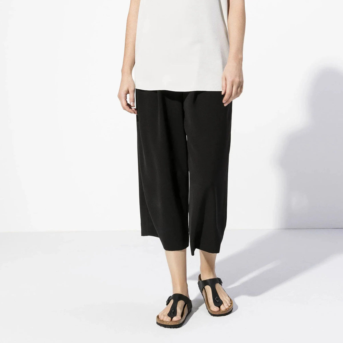 Pantaloni donna neri ampi alla caviglia con sandali bassi neri, stile minimal chic