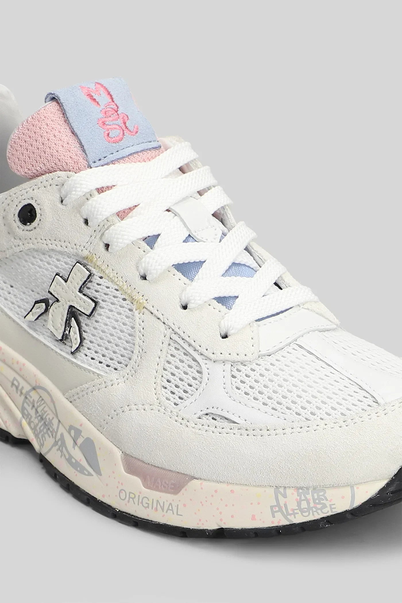 Sneaker bianca da donna con dettagli rosa e blu, tomaia in tessuto e pelle, suola decorata.