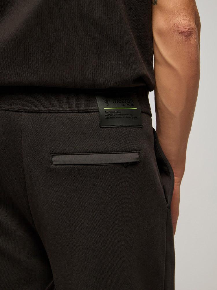 Dettaglio pantaloni uomo neri eleganti con tasca posteriore e targhetta logo.
