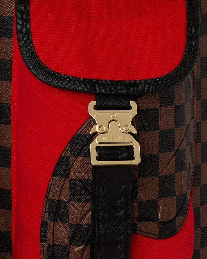 Dettaglio di borsa in tessuto rosso con motivo a quadri marroni e fibbia dorata elegante.