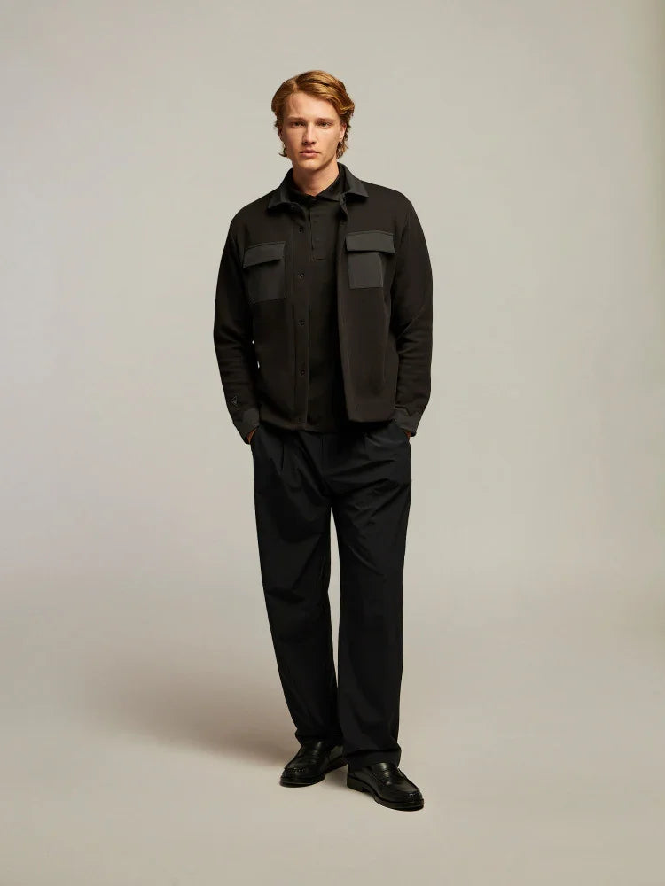 Modello uomo indossa giacca nera elegante, camicia nera e pantaloni classici, moda uomo.