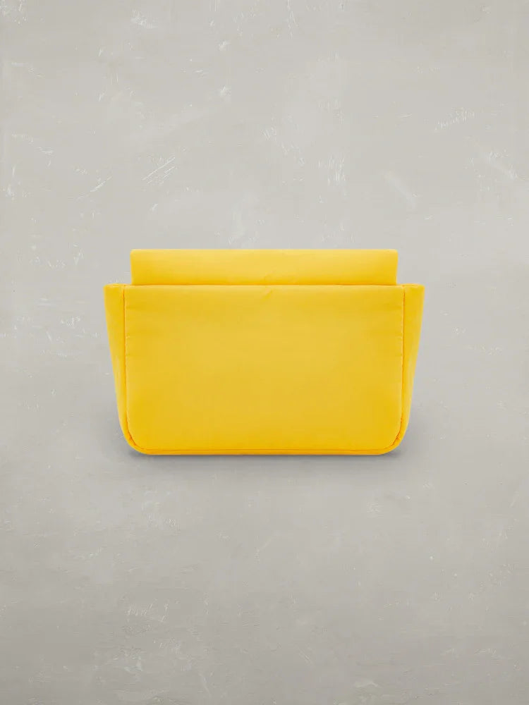 Pochette gialla da donna in tessuto, stile minimal, su sfondo grigio chiaro