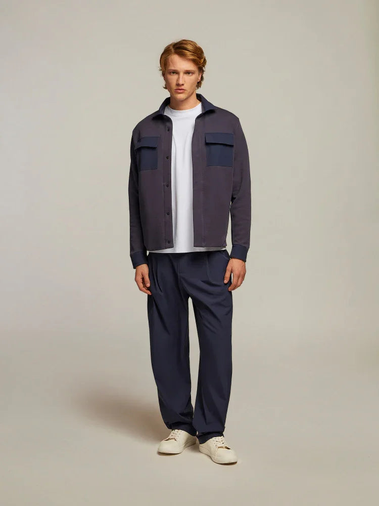 Uomo indossa camicia blu navy casual con tasche, t-shirt bianca e pantaloni coordinati eleganti.