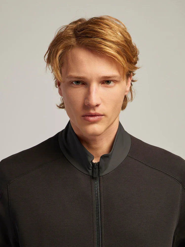 Giovane uomo con giacca sportiva nera con zip, moda uomo elegante, sfondo neutro