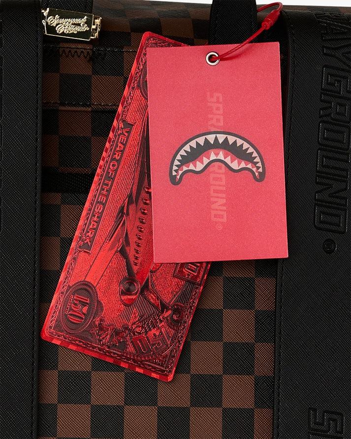 Dettaglio etichetta rossa su borsa a scacchi marrone e nero, accessorio moda uomo donna.