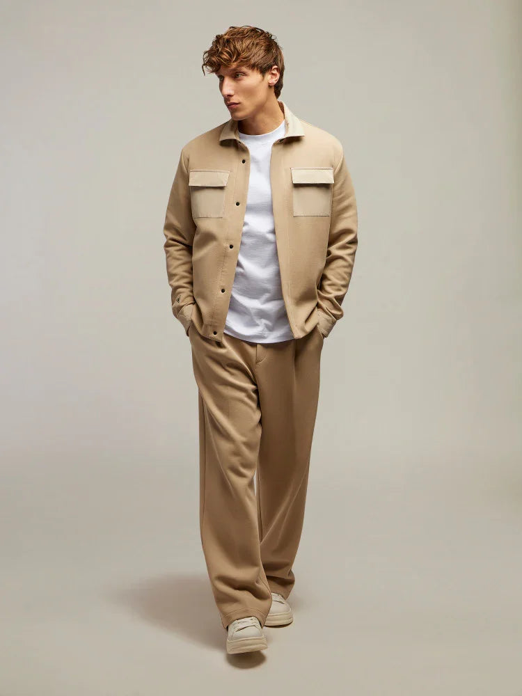 Modello uomo con giacca beige, pantaloni coordinati e t-shirt bianca, moda casual elegante