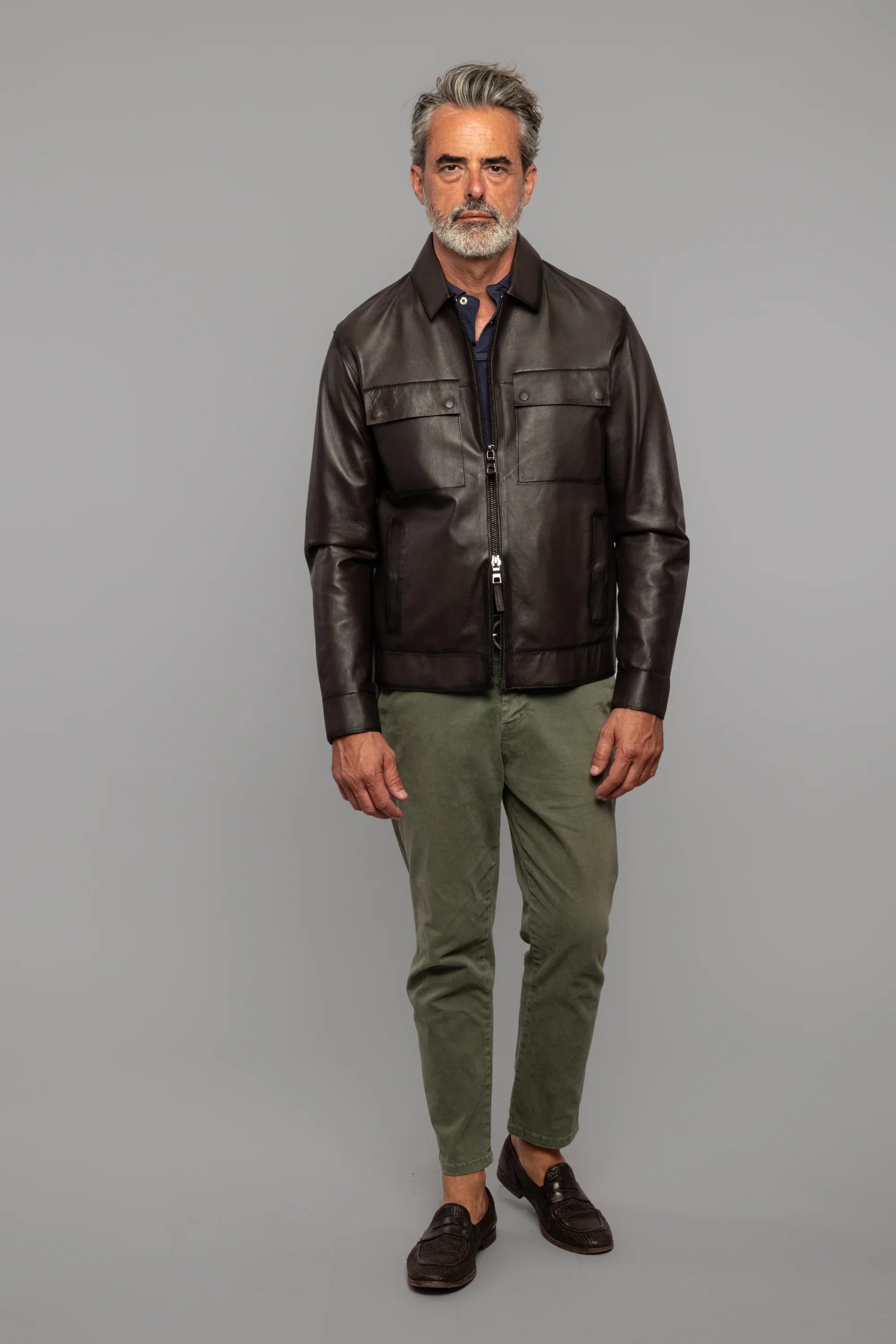 Uomo con giacca in pelle marrone, pantaloni verde oliva e mocassini, moda uomo elegante