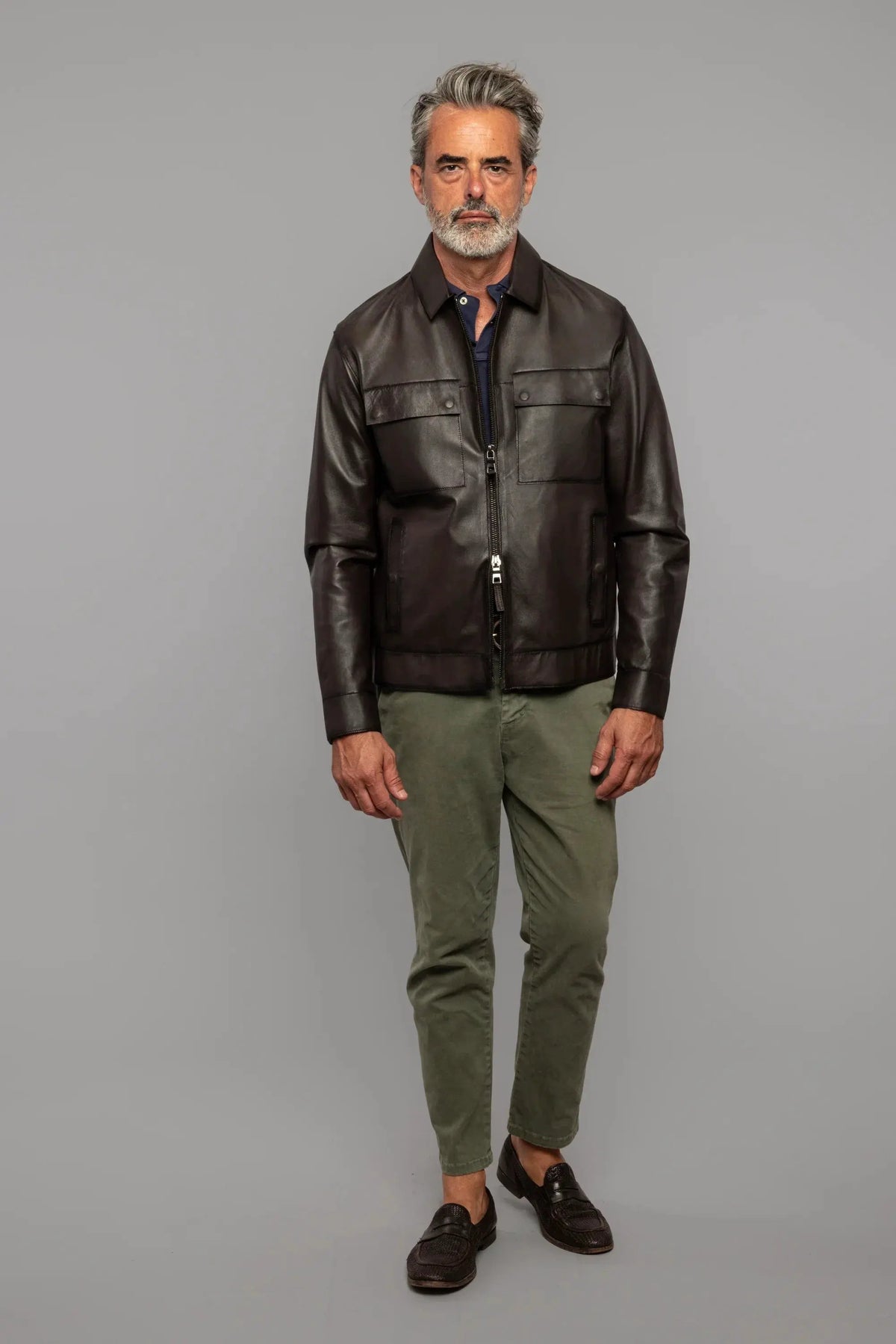 Uomo con giacca in pelle marrone, pantaloni verde oliva e mocassini, moda uomo elegante