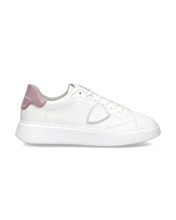 Sneaker donna in pelle bianca con dettaglio rosa sul tallone, suola piatta e design moderno.