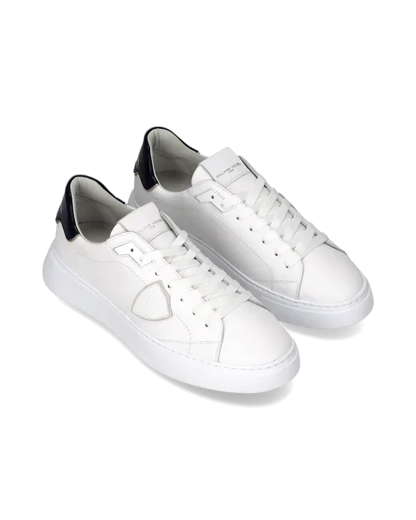 Sneakers uomo bianche in pelle con dettagli neri, stile casual elegante, vista diagonale.