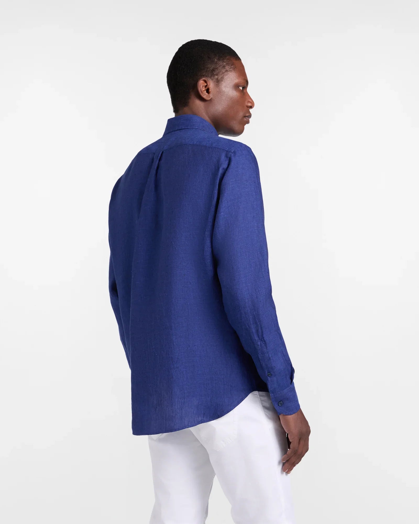 Camicia uomo lino blu maniche lunghe, vestibilità regular, abbinata a pantaloni bianchi eleganti.
