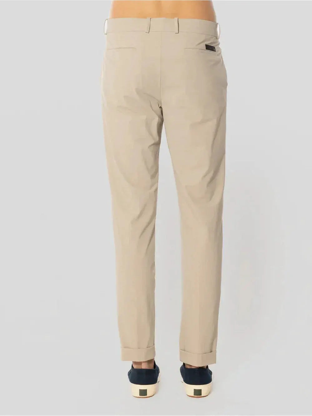 Pantaloni chino beige uomo eleganti, tasche posteriori e risvolto, su sfondo neutro.