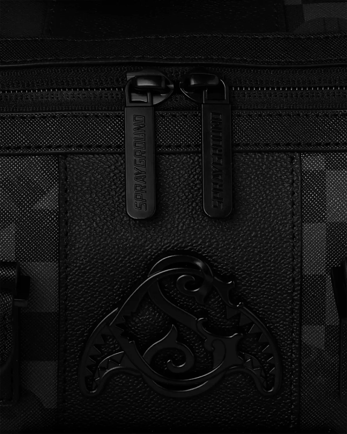 Dettaglio zaino nero Sprayground con doppia zip e logo in rilievo su tessuto strutturato