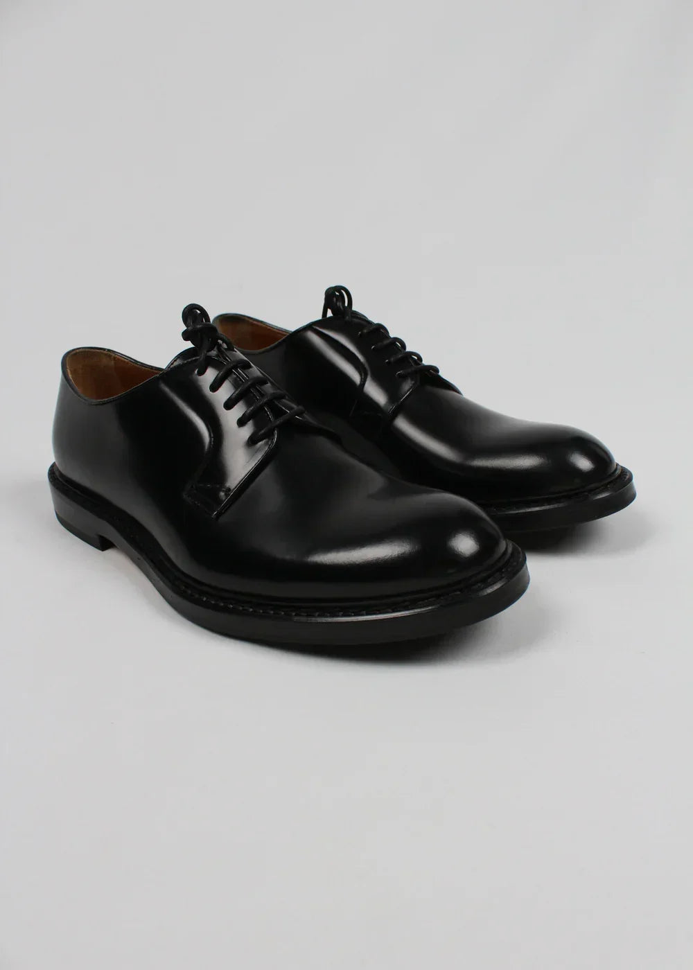 Scarpe derby uomo in pelle nera lucida, stile classico elegante, su sfondo neutro.