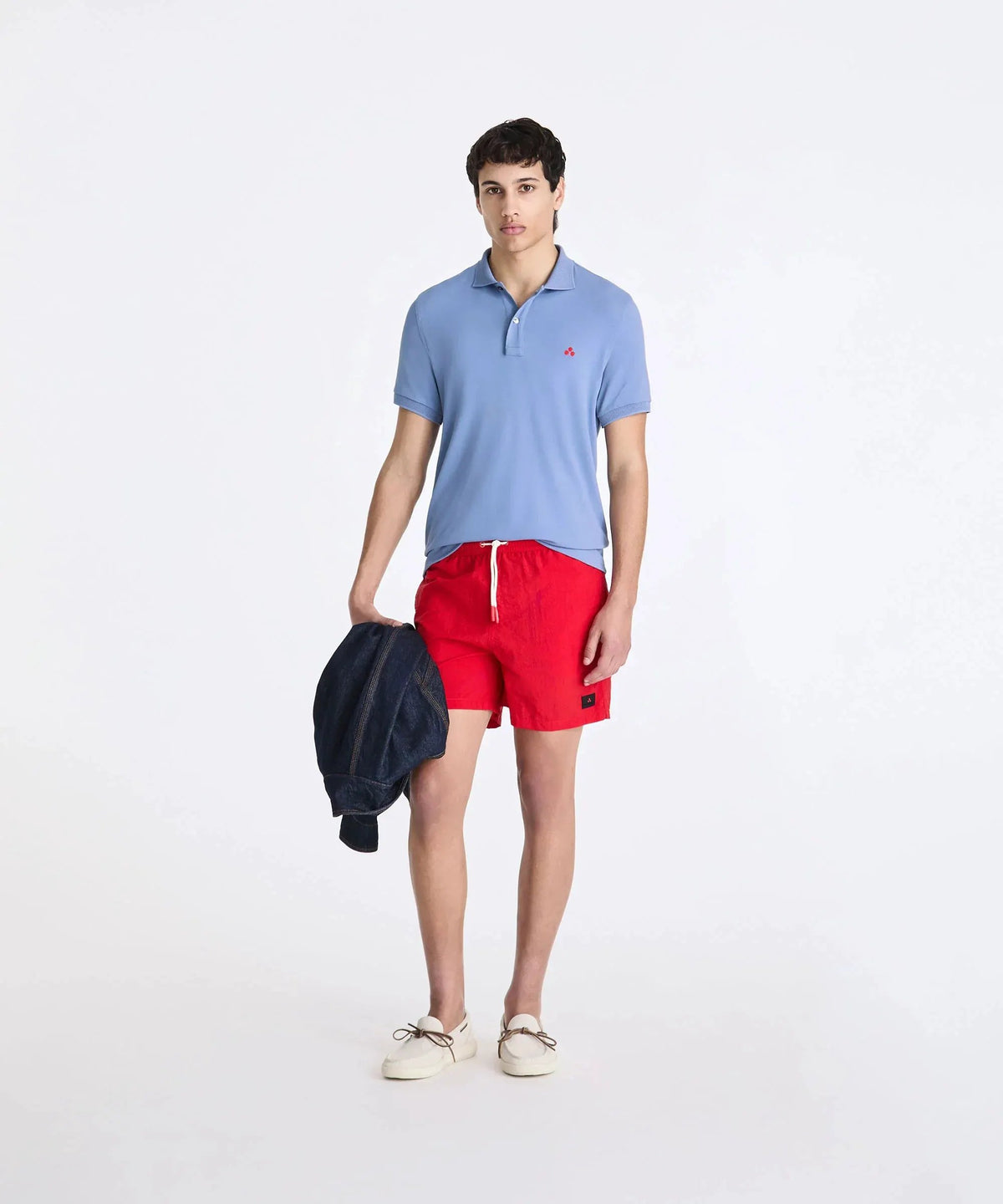 Uomo con polo azzurra, shorts rossi e mocassini bianchi, stile casual estivo