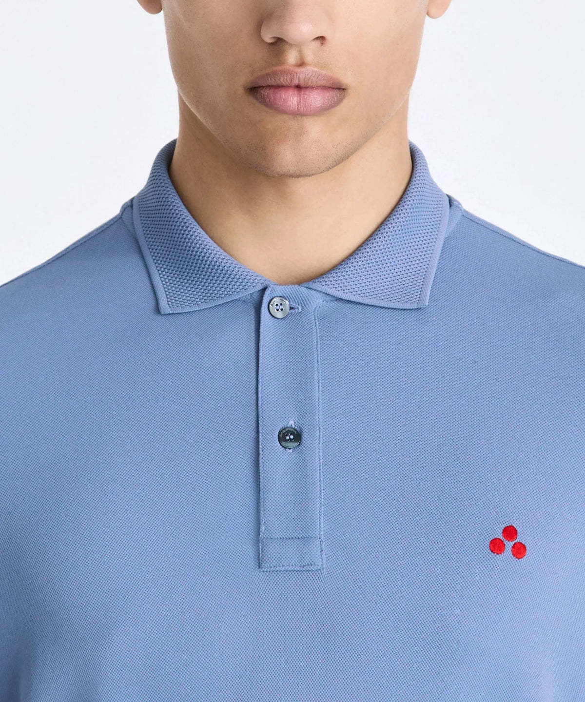 Polo uomo azzurra in cotone con piccolo logo rosso ricamato, colletto classico e bottoni.