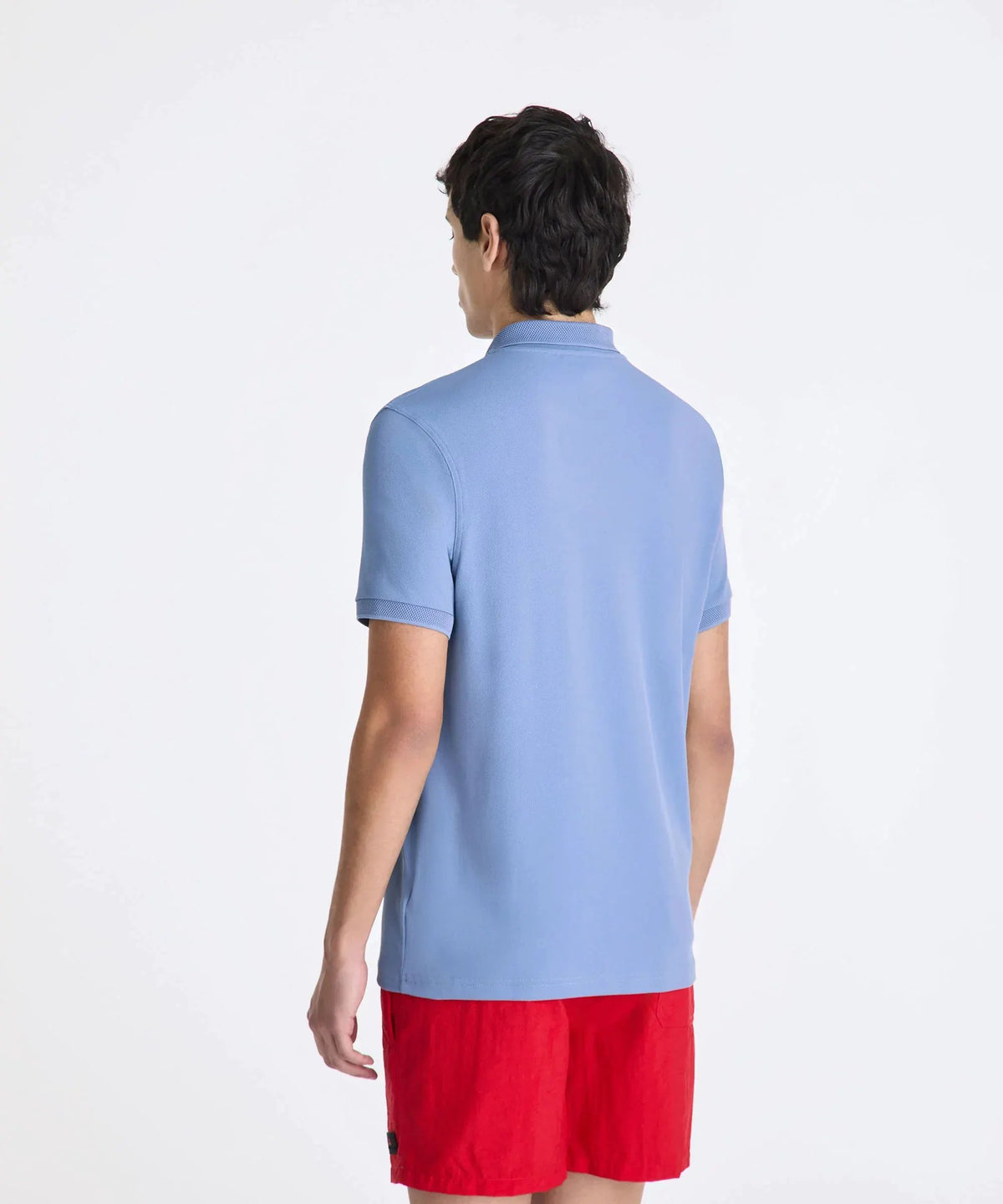 Uomo di spalle con polo azzurra e bermuda rossi, abbigliamento casual estivo