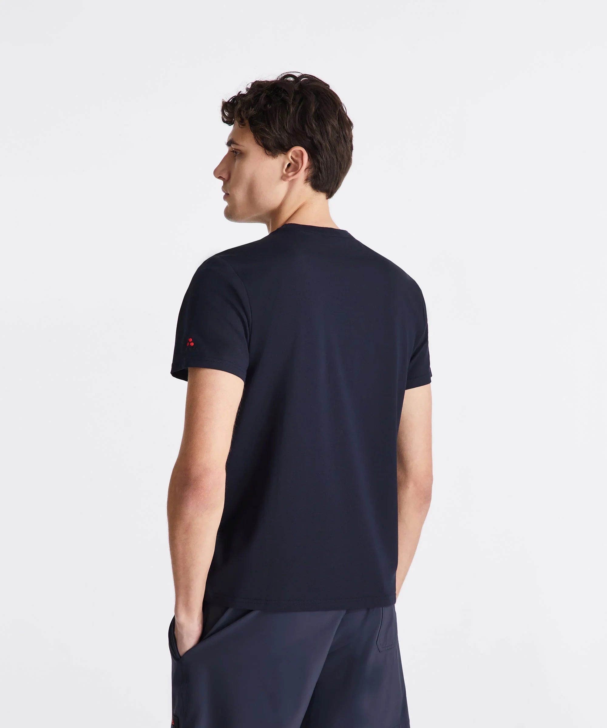 Modello uomo di profilo con t-shirt nera manica corta, sfondo bianco minimal