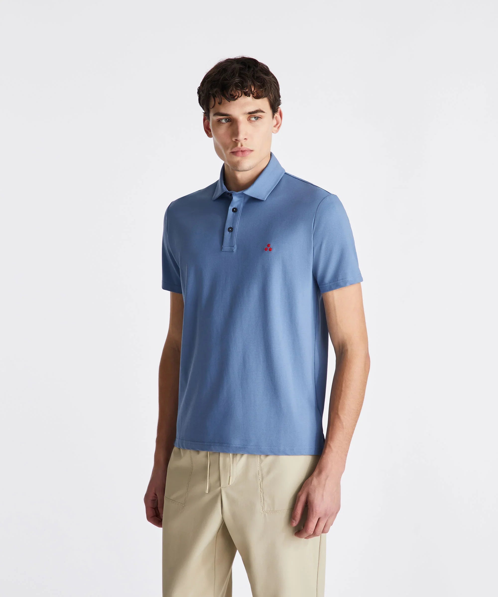 Polo uomo azzurra in cotone con bottoni, logo rosso e pantaloni beige, moda primavera estate