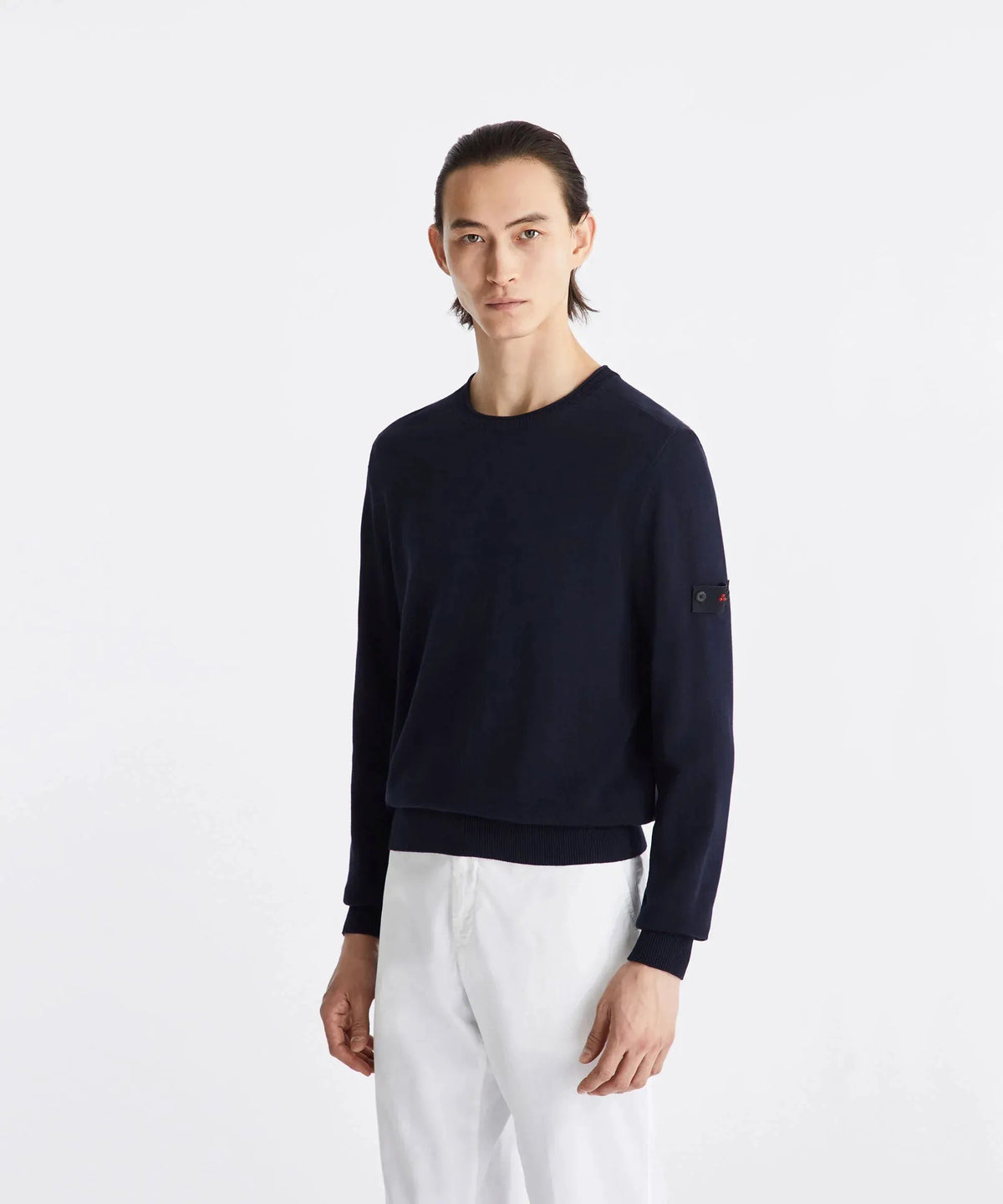Maglione uomo blu scuro a maniche lunghe, vestibilità regular, indossato su pantaloni bianchi, stile elegante casual.