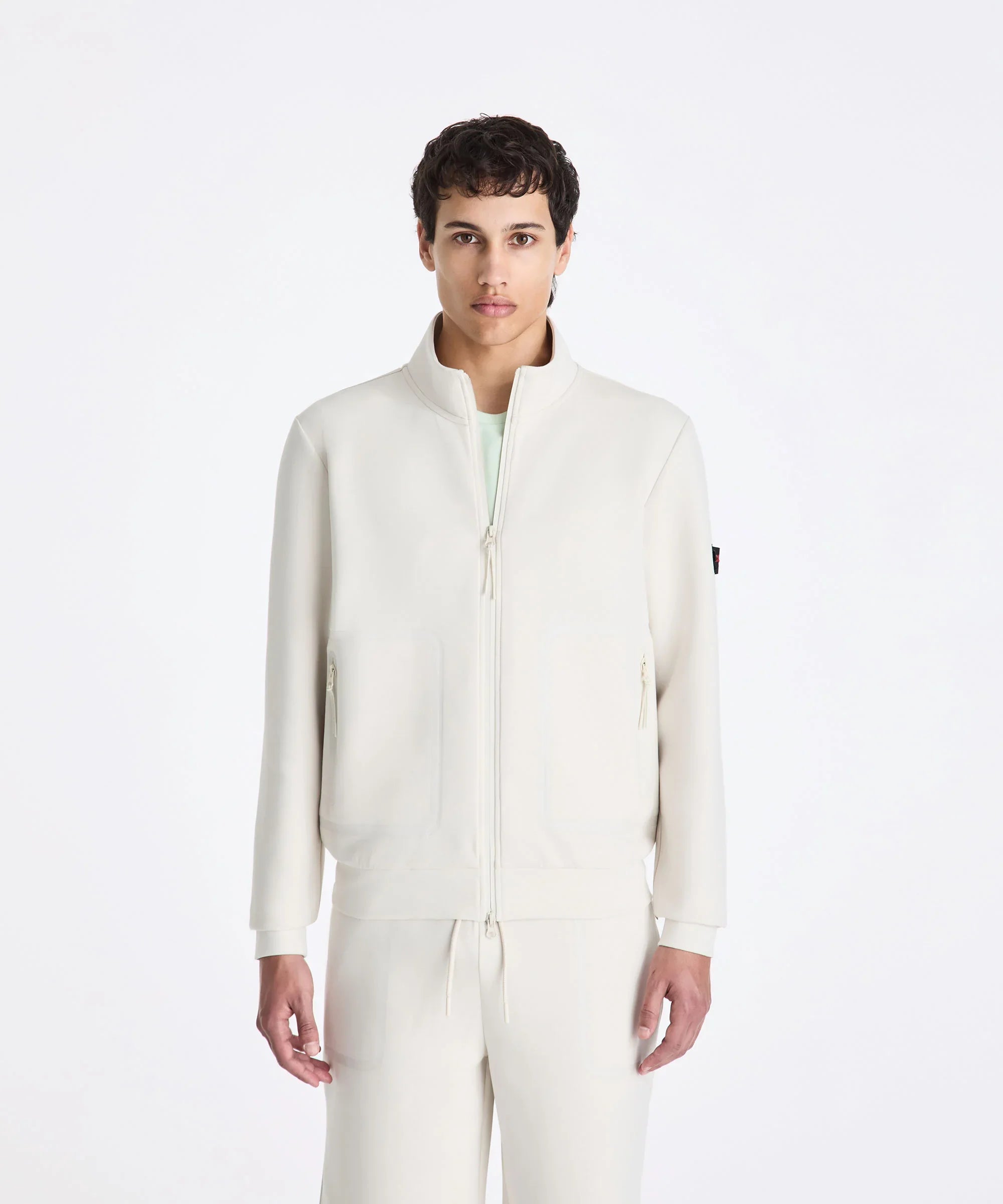 Modello con giacca e pantaloni bianchi sportivi da uomo, stile minimal, sfondo neutro