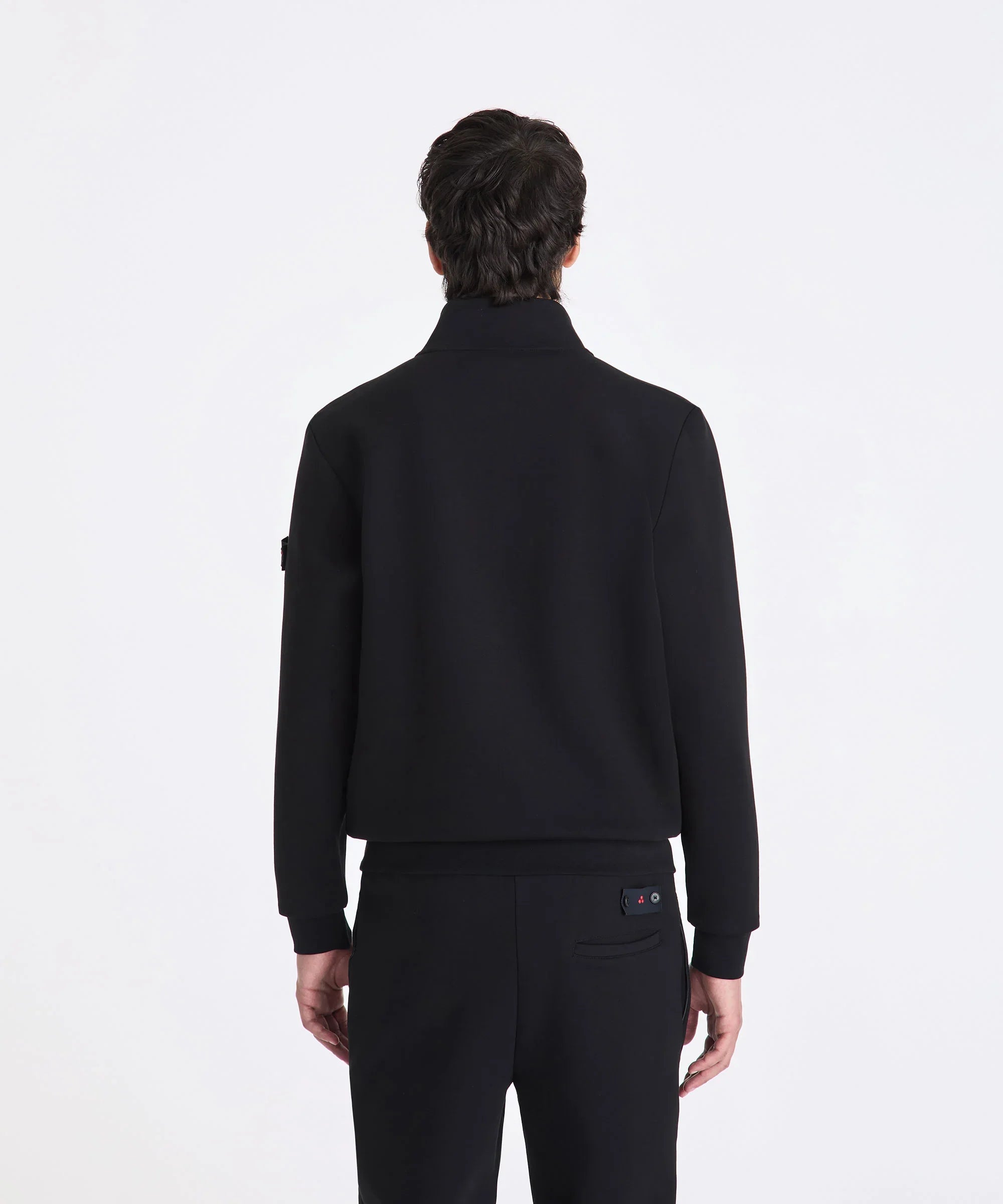 uomo di spalle con giacca nera elegante e pantaloni neri, sfondo bianco