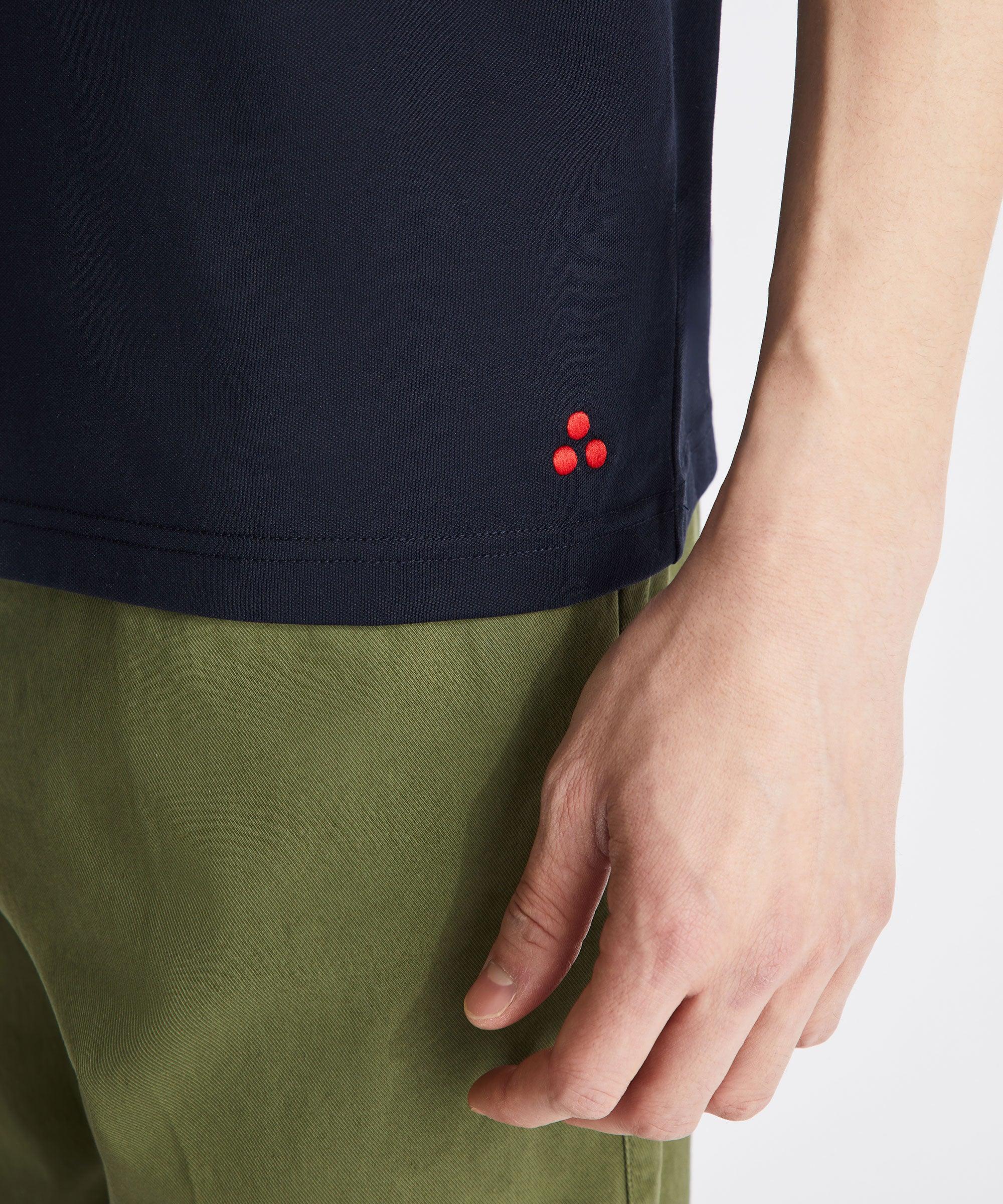 Polo blu uomo con dettaglio rosso sul fondo, pantaloni verdi, abbigliamento casual.