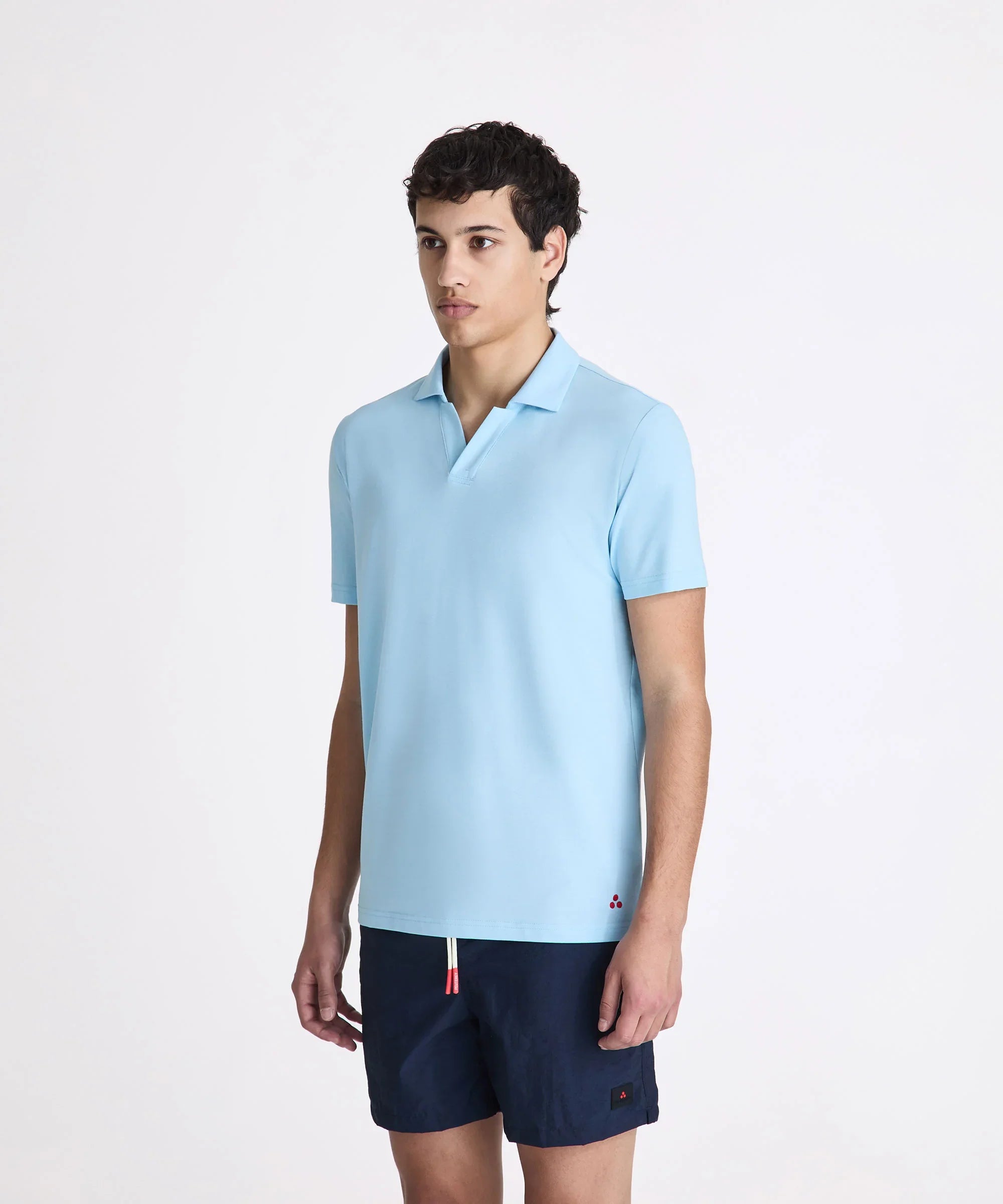 Uomo con polo azzurra a maniche corte e pantaloncini blu navy, moda uomo estiva
